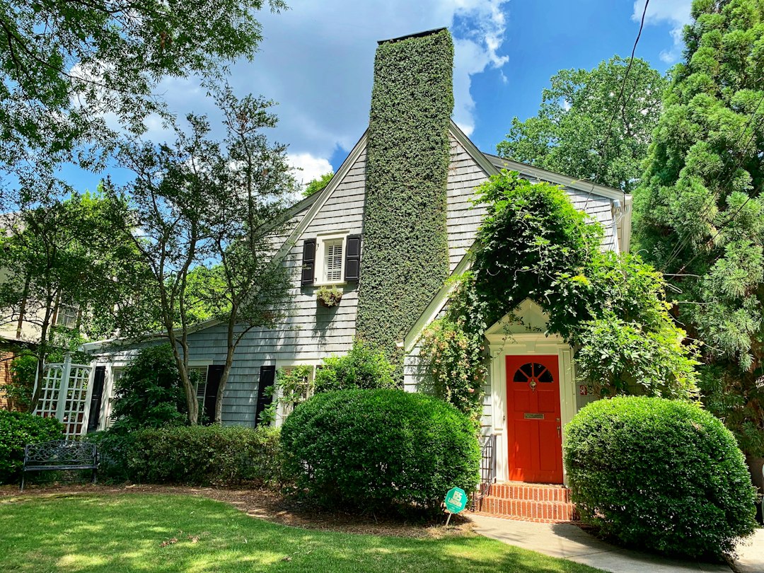 Classic Atlanta bungalow-style home with a 'For Sale' sign in the front yard on a bright, sunny day, representing the loca...