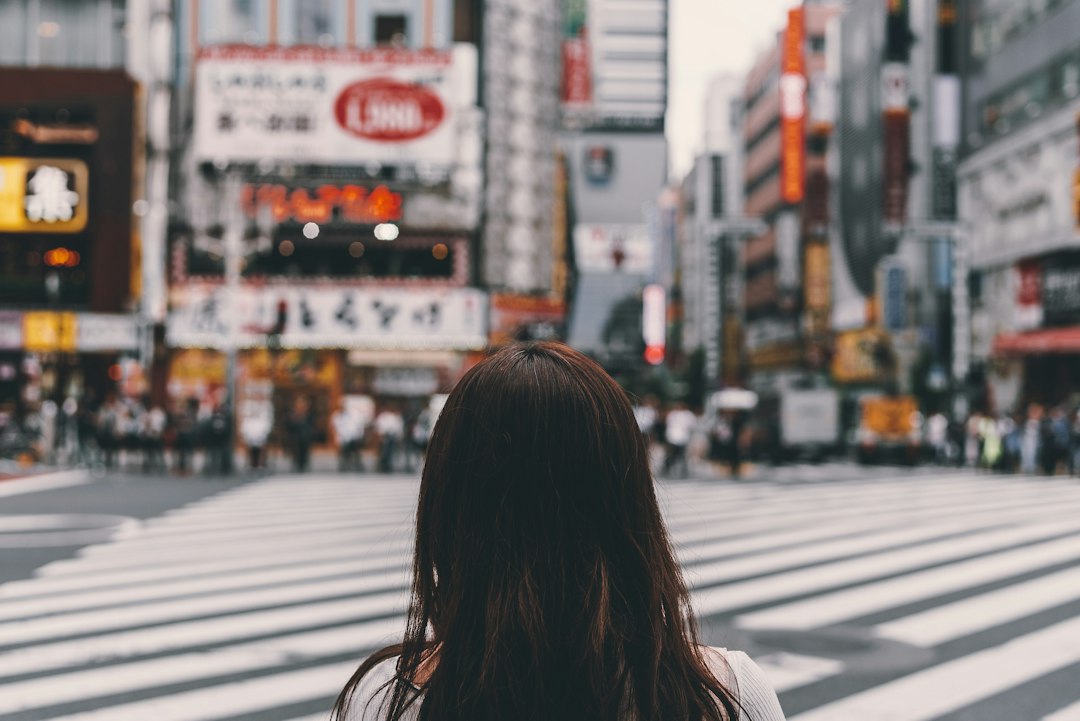 Person stands thoughtfully at a fork in the road, symbolizing the difficult decision a home seller must make between price...