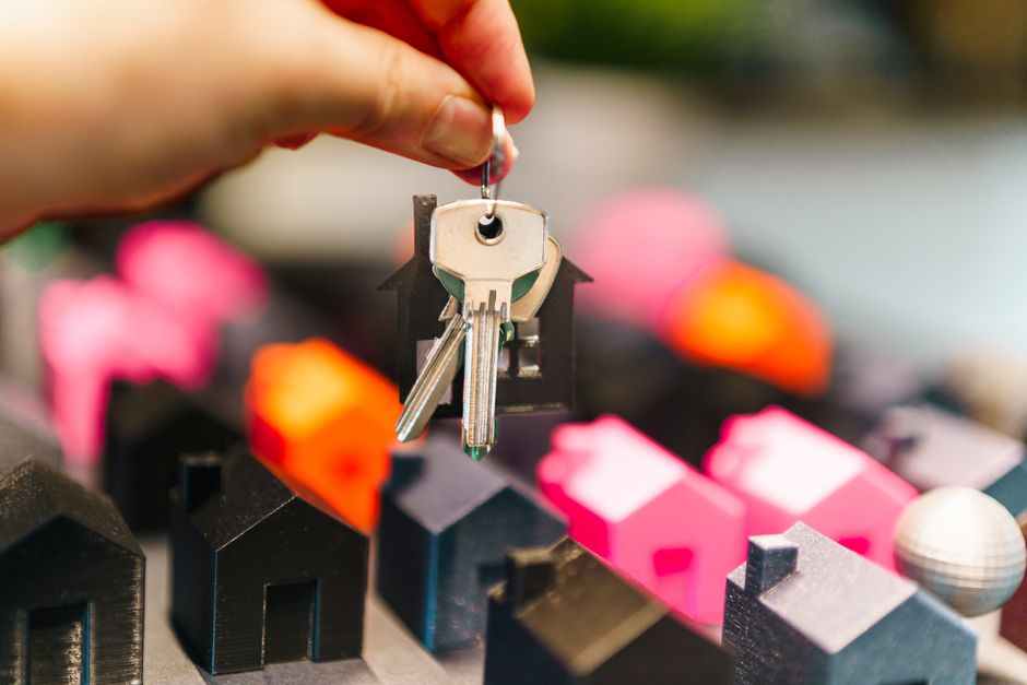 A stopwatch sits next to a set of house keys on a clean, modern surface, representing the choice between selling a home quickly or for the right price.